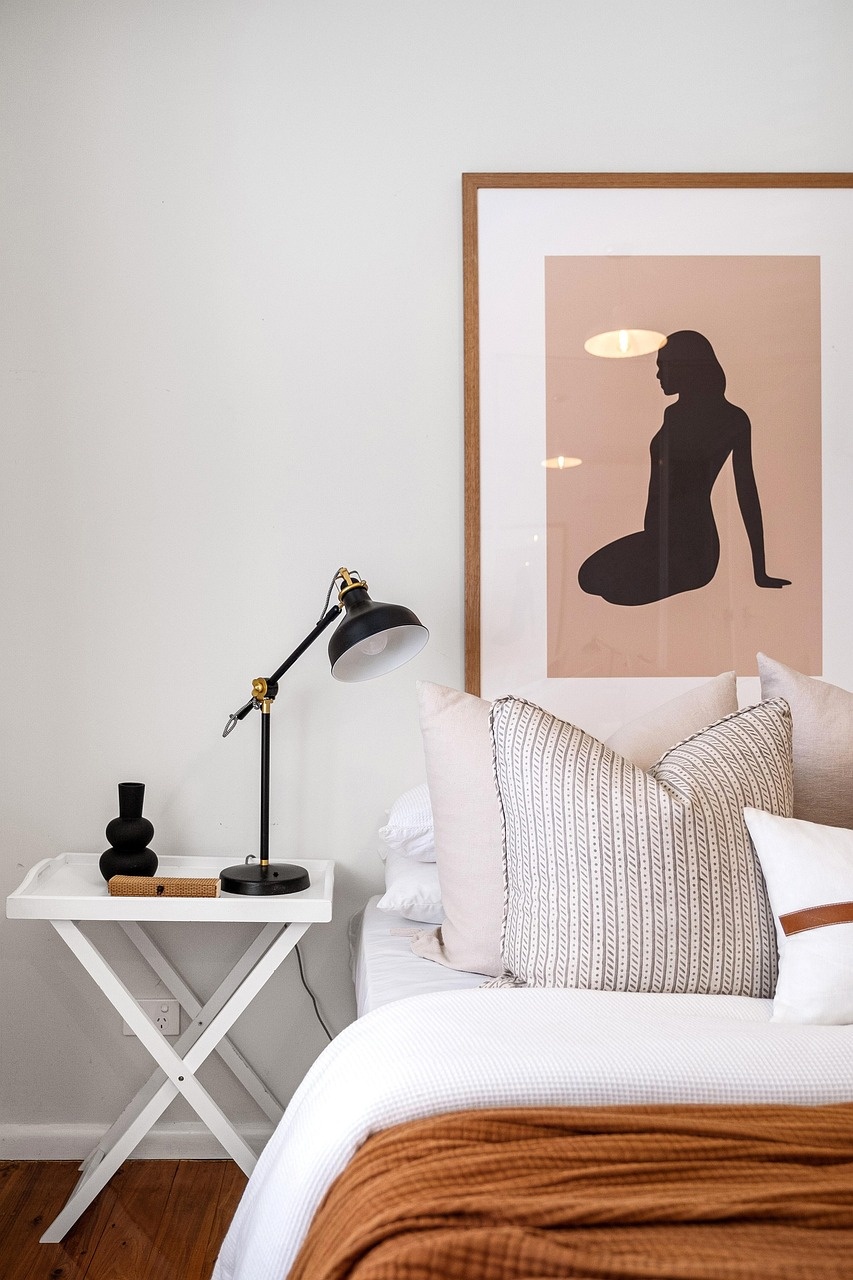 Boutique bedroom corner with striped cushions, leather-strap pillow and brass lamp