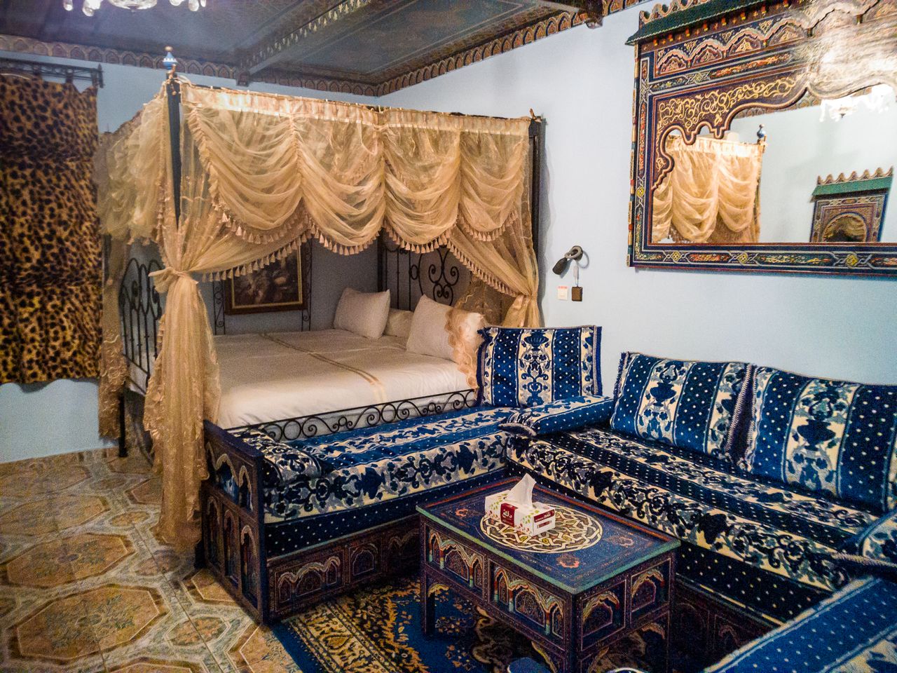 Signature suite with canopy bed, patterned blue seating and carved tables
