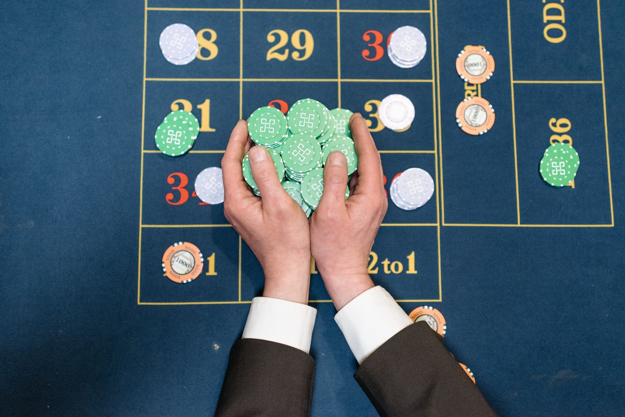 Hands holding green chips above a roulette grid
