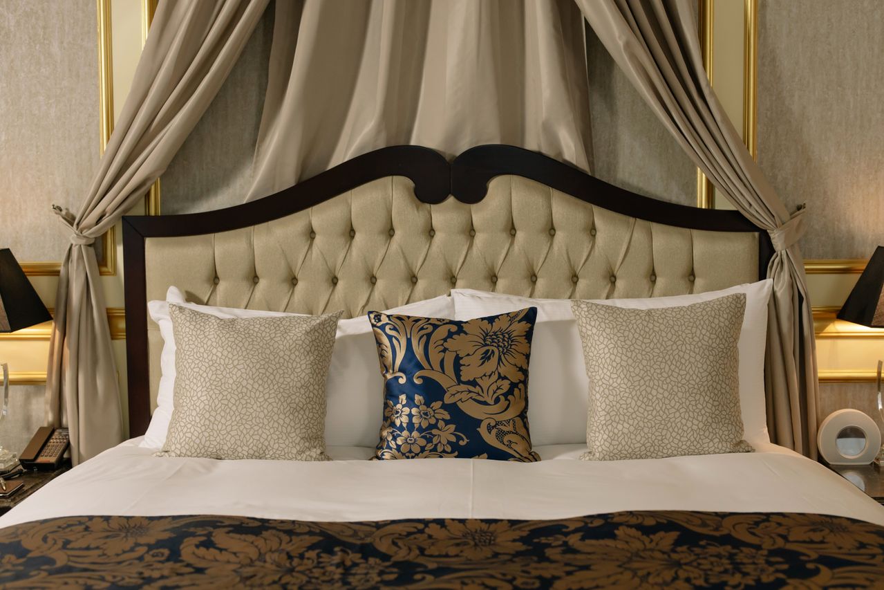 Tufted champagne headboard with midnight-blue damask cushions and brass moulding