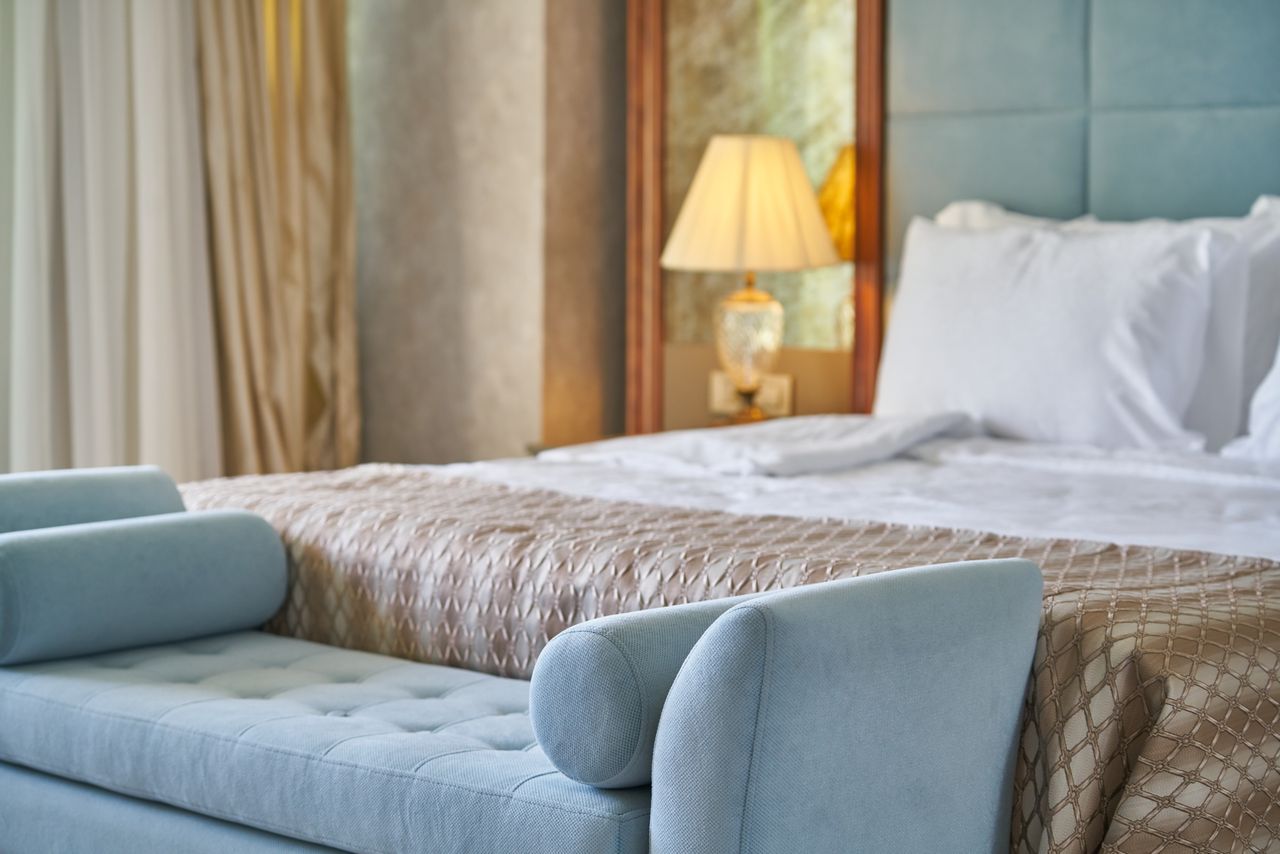 Powder-blue velvet bench and champagne linens in a quietly lit Marellune suite