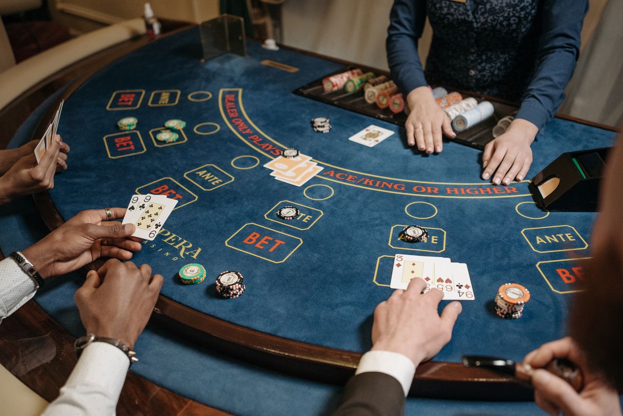 Card table with ante markings, chips and players’ hands around a wooden rim