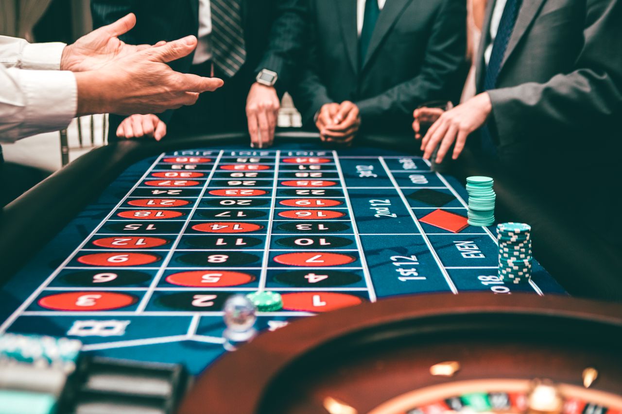 Guests in evening dress gathered around a midnight-blue roulette table